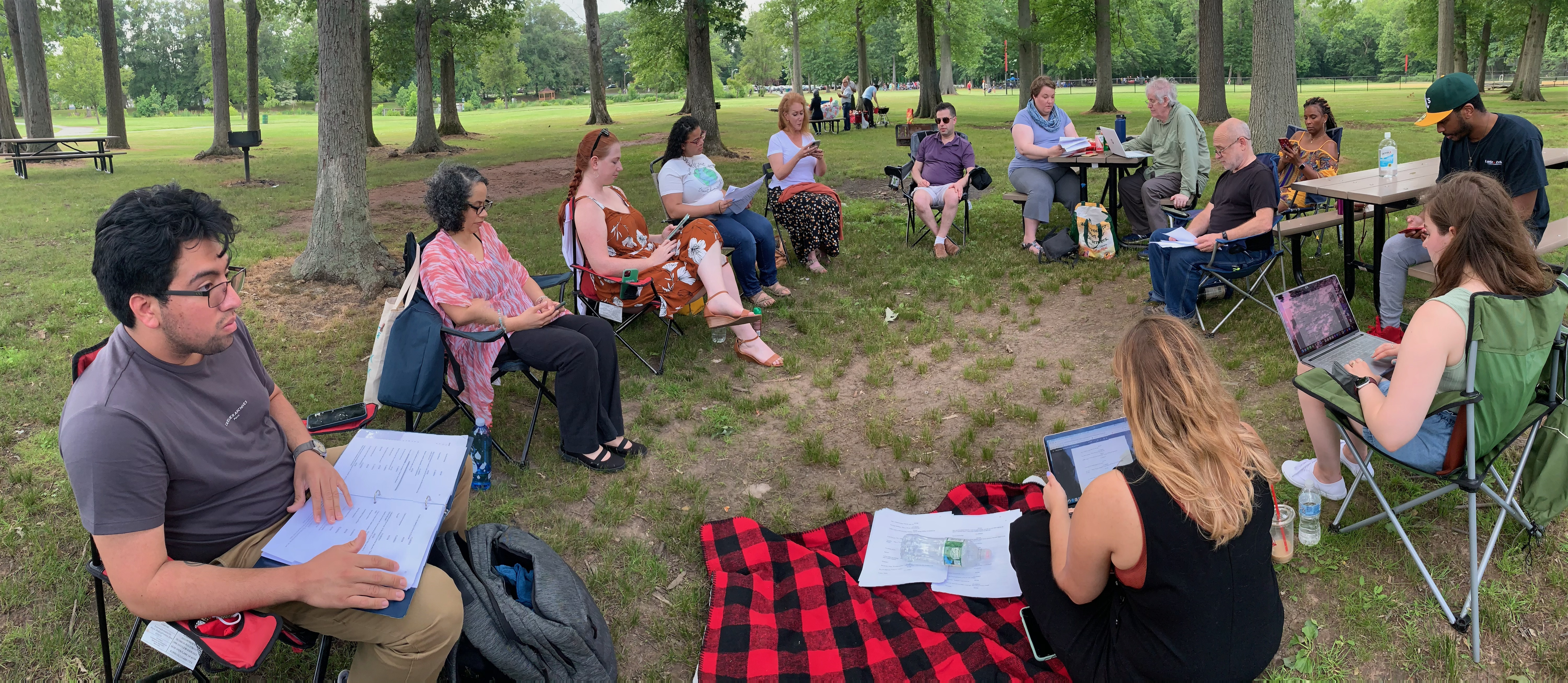 Image of actors sitting in a circle outdoors.